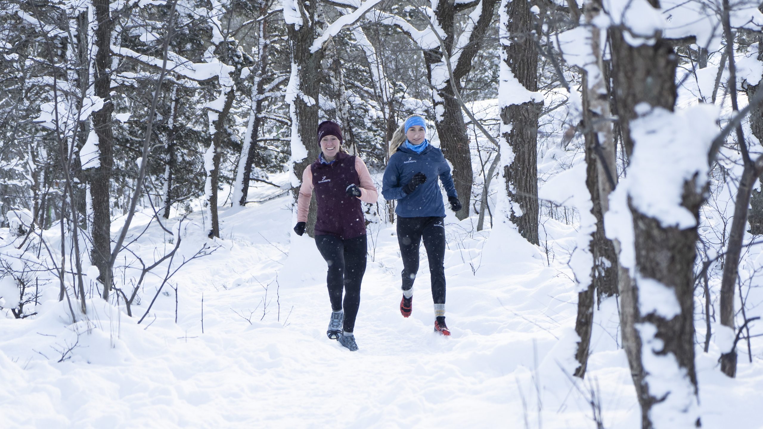två tjejer springer i snön