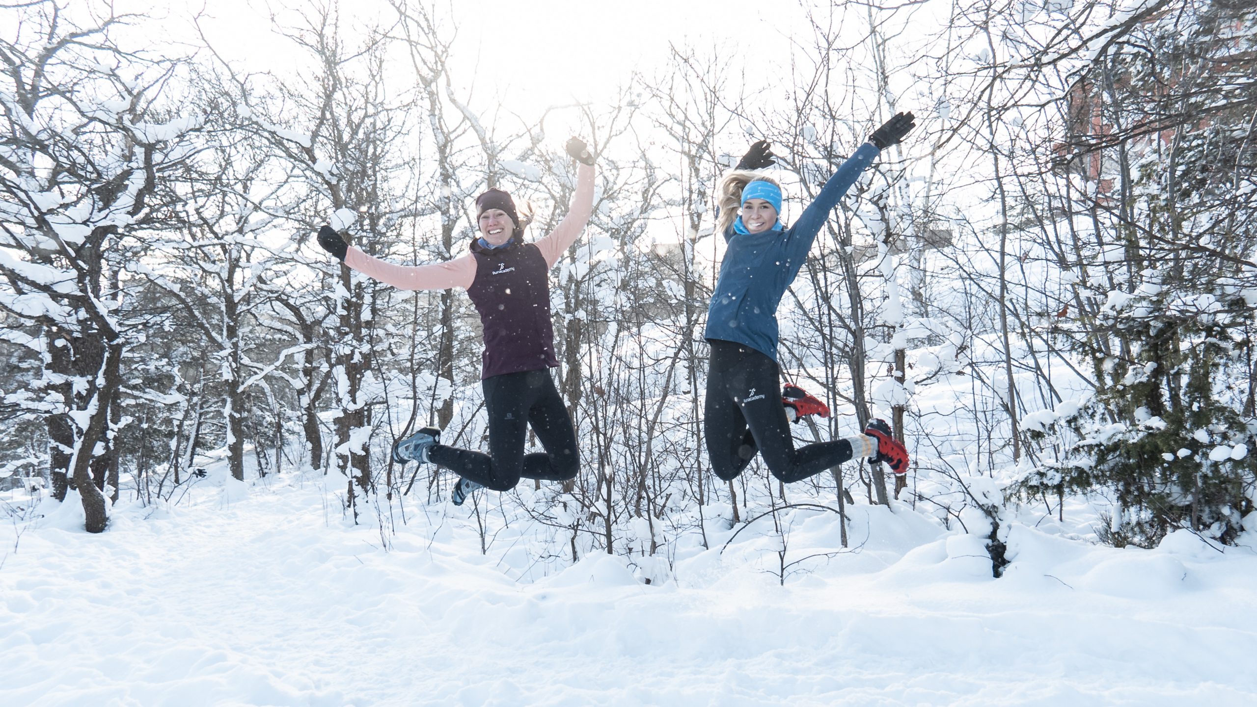 Två glada tjejer hoppar i snön
