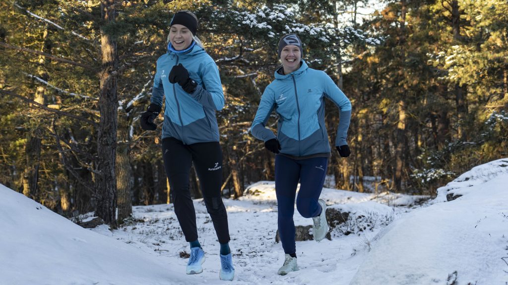 Två tjejer springer i snön