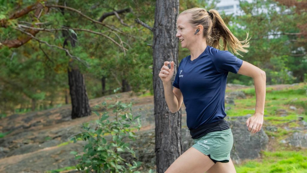 Tjej springer i skogen med bra löpteknik