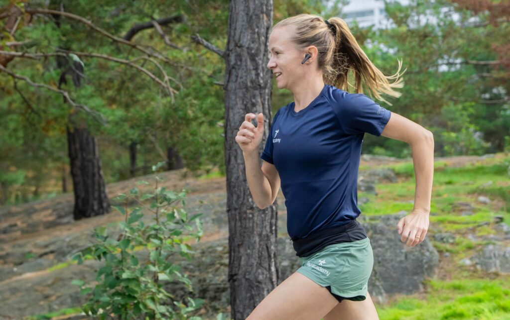 Tjej springer i skogen med bra löpteknik